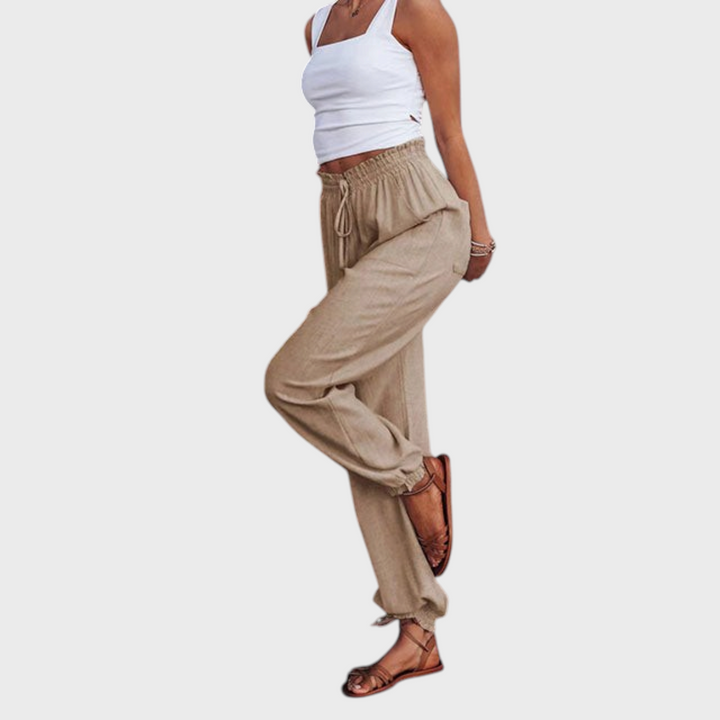 Modelo veste calças de jogging Liselotte Salzburg em bege, com cintura subida, cordão ajustável e bainhas elásticas.