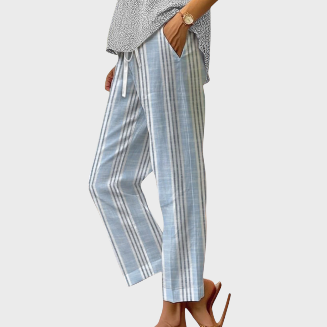 Calças casuais Liselotte Salzburg com riscas verticais azuis e brancas, corte largo, cintura elástica e bolsos laterais.