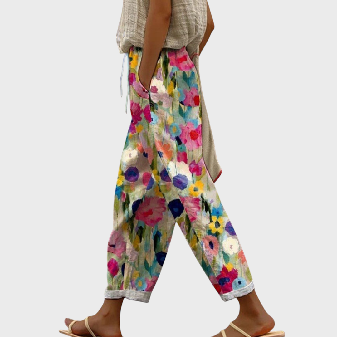 Calças Liselotte Salzburg com padrão floral colorido, corte largo, cintura elástica e bolsos laterais profundos.