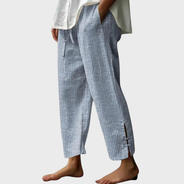 Calças Liselotte Salzburg Bellie em algodão azul com riscas verticais, cordão na cintura e bainha com fenda lateral.